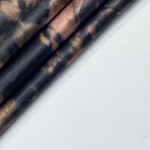 Détail du tissu tie-dye doux avec motifs noirs et orange et texture satinée subtile