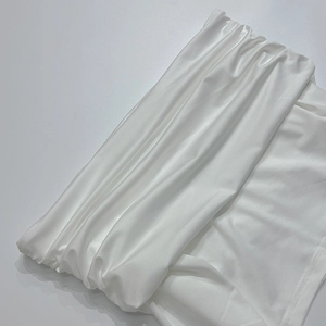 Detailweergave van de witte satijnen stof met geplooide textuur en zijdeglans