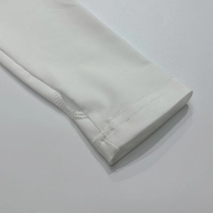 Detail van witte crop top met dubbelnaalds stiksel en versterkt duimgat voor extra comfort