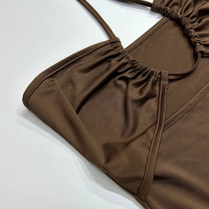 Gros plan détaillé d'une robe marron à licou montrant l'encolure froncée et le tissu soyeux