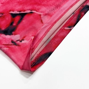Détail de la couture surjetée sur le tissu imprimé tie-dye rose de la robe moulante