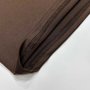 Detailed close-up of double-needle stitching on deep brown long sleeve top hemline