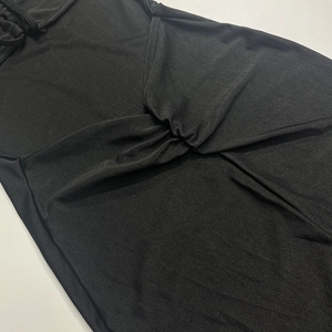 Détail du tissu en maille noire avec un design torsadé et des plis naturels sur la robe