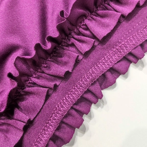 Détail macro d'une robe violette à volants montrant les finitions de couture surjet