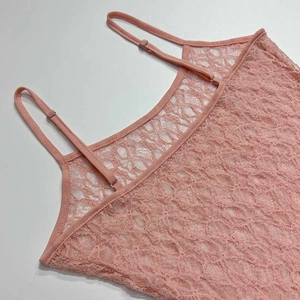 Détail du tissu en dentelle florale rose avec de fines bretelles réglables sur la robe