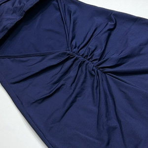 Détail du tissu bleu foncé présentant un décolleté en V élégant et des textures plissées