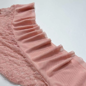Détail de broderie en dentelle rose et de volants en maille transparente sur la robe