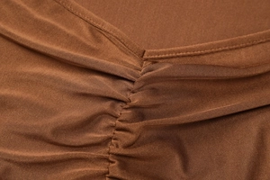 Détail du décolleté en V avec fronces sur une robe longue dos nu en tricot marron