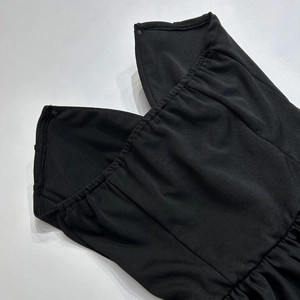 Détail du décolleté en V et du corsage plissé sur une robe noire bustier de soirée