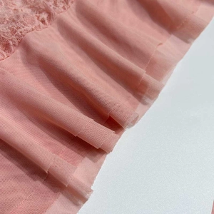Détail macro de dentelle rose clair et texture de maille plissée sur la robe de soirée