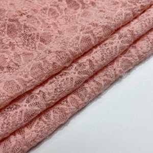 Détail du tissu en dentelle florale rose avec broderie fine et texture transparente