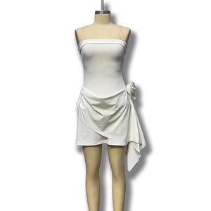 Détail de la robe bustier blanche avec fleur 3D et jupe portefeuille asymétrique plissée