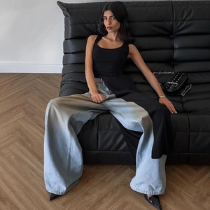 Chic black sleeveless top with high side slit paired with wide leg light blue denim jeans
