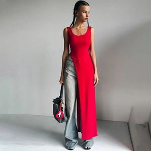 Red sleeveless long top with high side slits and wide-leg jeans on a model in a minimalist studio