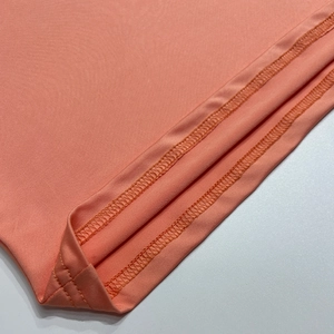 Detail of coral orange knit dress hem with high-quality double-needle stitching