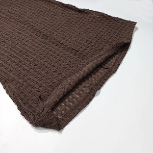 Detail shot of brown pleated knit fabric with unique seersucker texture and hemline