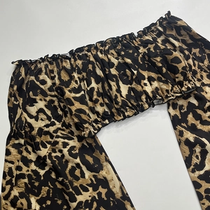 Detail van top met luipaardprint, off-shoulder elastische halslijn en ruchesrand