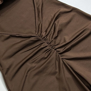 Gros plan sur un body marron foncé avec décolleté en V, plis et texture de tissu élastique