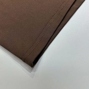 Gros plan détaillé du tissu marron foncé montrant les coutures fines et la maille
