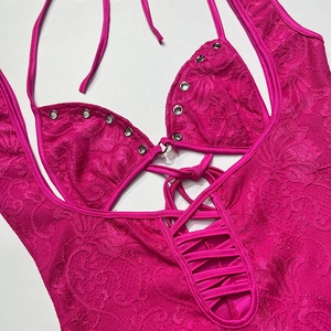 Détail d'un body en dentelle rose rouge avec licou, œillets métalliques et dentelle évidée