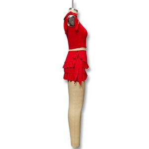 Dettaglio del crop top rosso senza maniche con fiocchi e minigonna a balze a strati