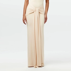 Detail of nude slim-fit maxi dress featuring center knot waist and elegant pleats