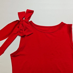 Dettaglio del top rosso senza maniche con un grande fiocco sulla spalla e cuciture