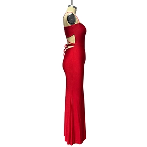 Détail d'une robe longue rouge moulante avec découpe latérale et laçage croisé à la taille