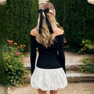 Detail of off-shoulder puff dress with black bodice and white skirt in garden setting