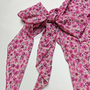 Detailed view of floral chiffon dress with a large decorative bow and purple flower print