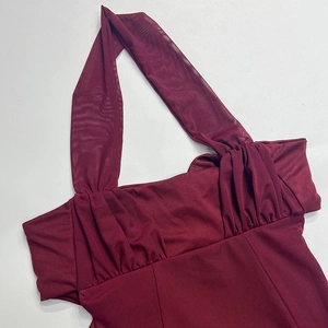 Detail of burgundy halter neck dress featuring sheer mesh trim and pleated bust texture