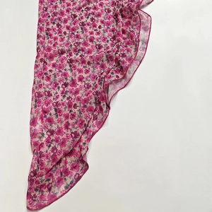 Detailed view of floral print and ruffled hem on a light pink chiffon summer dress