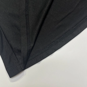 Détail des coutures et de la finition de l'ourlet sur le tissu textile noir de la robe