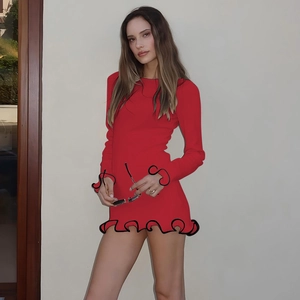 Détail de robe rouge à manches longues avec bordure ondulée noire et coupe en maille
