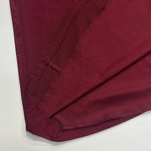 Detail of the stitching and breathable burgundy mesh fabric texture on the dress hemline