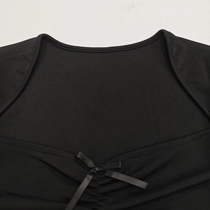 Dettaglio di un elegante scollo nero con spalle scoperte, fiocco in raso e pieghe