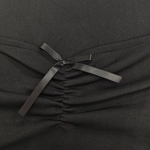 Dettaglio ravvicinato di un abito in maglia nera con fiocco in raso e texture increspata