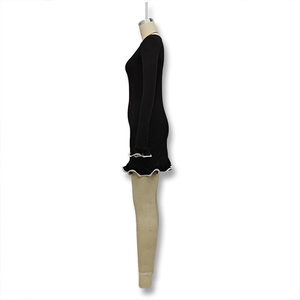 Détail de la robe tricotée noire avec ourlet à volants blancs et contraste aux manches