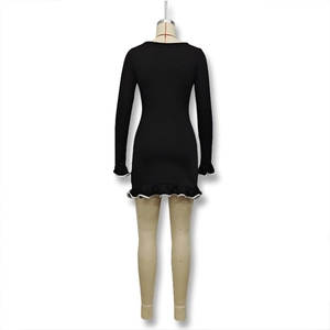 Détail de la robe en maille noire avec volants bordés de blanc aux poignets et à l'ourlet