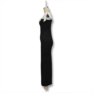 Detail view of a black slim-fit maxi dress featuring a white bow accent on the neckline
