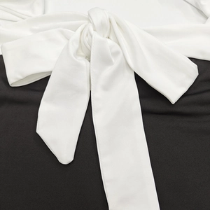 Detail shot of wide white decorative tie-knot on black slim fit bodycon dress