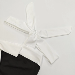 Detailed view of the elegant white lapel collar and lace-up bow tie on this chic black dress