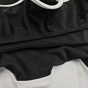 Gros plan sur les coutures contrastées et la texture du tissu en maille noire de la robe