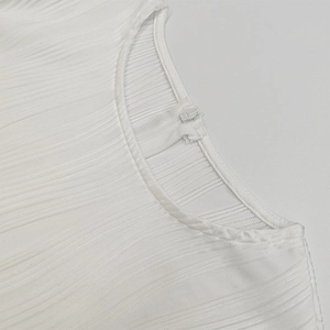 Detailed close-up of a white pleated dress featuring a round neck and invisible back zipper