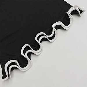 Détail du tissu en maille noire avec ourlet volanté blanc et bordure festonnée élégante
