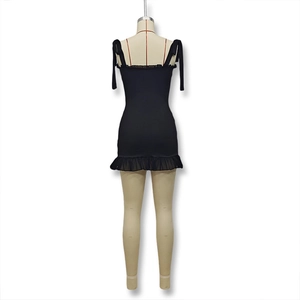Detail of black bodycon mini dress showing tie-up spaghetti straps and ruffled hem detail