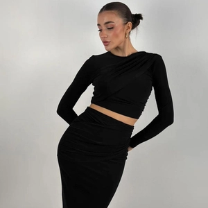 Detail of black knit two-piece set featuring ruched long sleeve top and midi skirt texture