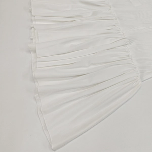 Detail view of high-density vertical pleated white dress fabric and fine edge stitching
