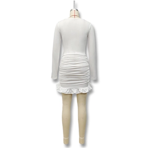Detalle de vestido blanco de manga larga con cuerpo fruncido y elegante bajo volantes