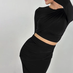 Detail view of black long sleeve crop top with side pleats and ruched midi skirt set
